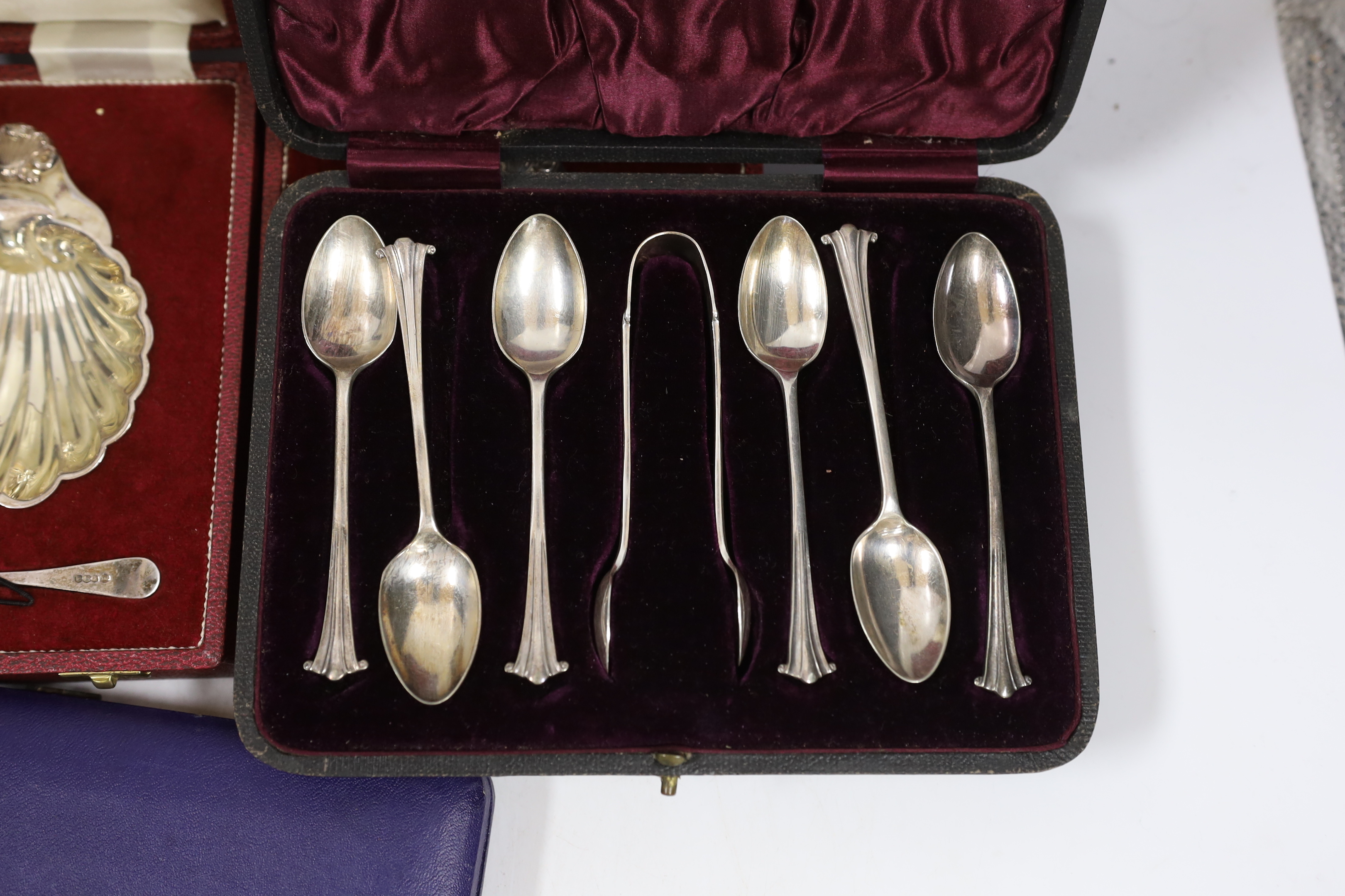 Two modern silver cased shell and butter knife sets, a cased silver five piece condiment set, a cased set of six silver teaspoons with tongs, one other cased silver butter shell and knife and a cased set of plated teaspo